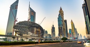 Cityscape of Dubai featuring futuristic architecture including the iconic Museum of the Future and surrounding skyscrapers under a clear sky.