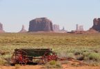 Old wooden wagon in a desert landscape with Monument Valley rock formations in Utah, ideal for outdoor adventure enthusiasts and nature lovers.