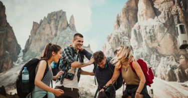 Group of four happy hikers with backpacks and cameras enjoying their adventure near rugged mountain peaks at Mount Roraima.