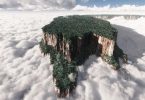 Majestic aerial view of Mount Roraima, covered in lush greenery, rising above the clouds, illustrating the allure of a luxurious helicopter tour experience in 2025.