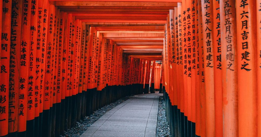 Rows of vermilion torii gates forming a tunnel pathway at Fushimi Inari Shrine in Kyoto, Japan.