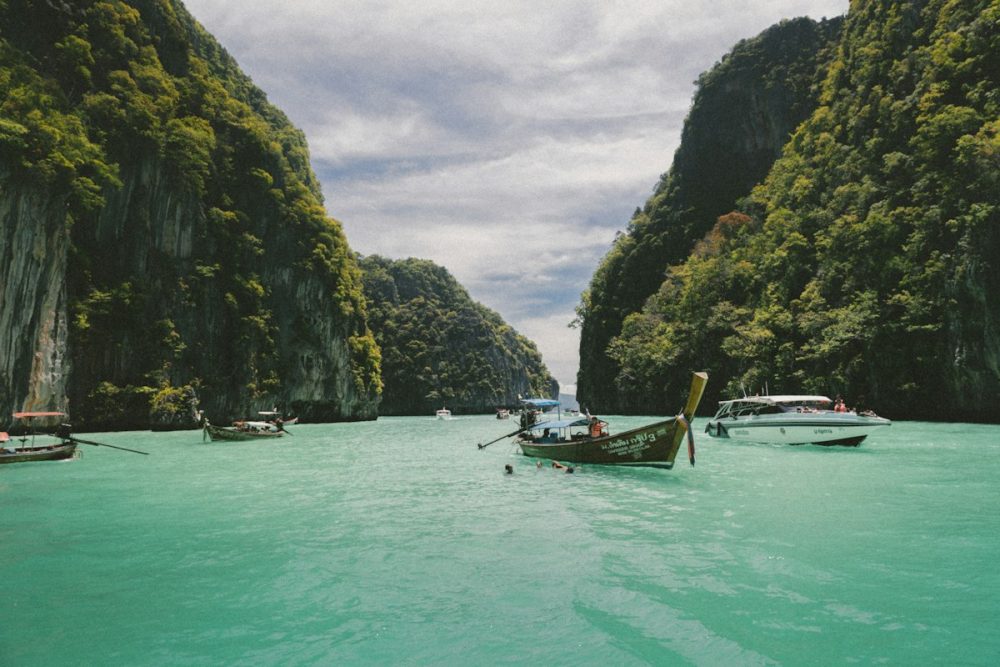 Longtail boat on the clear turquoise water of the Phi Phi Islands with limestone cliffs behind